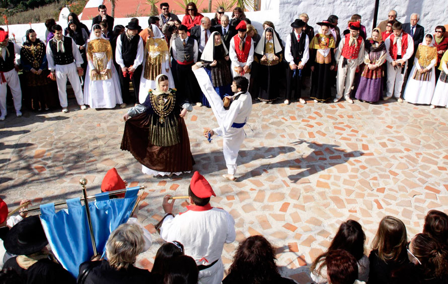 Mientras los bailadores saltan y se mueven dinámicamente con los brazos y las piernas, las bailadoras se mueven a su alrededor formando círculos con pasos cortos y rítmicos.